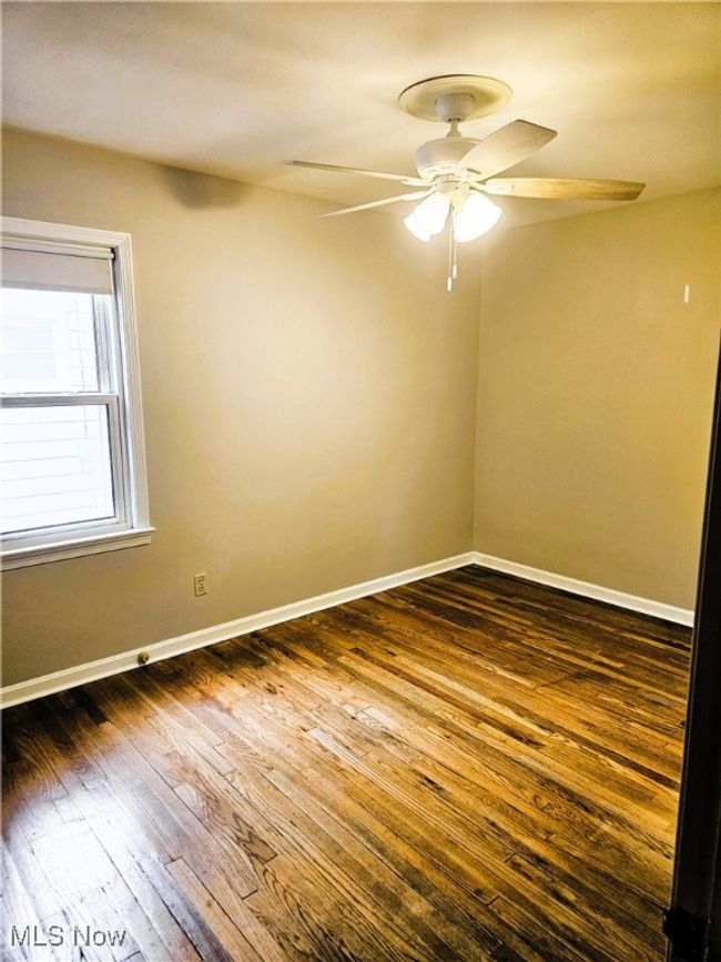 Empty room featuring ceiling fan, dark wood-type flooring, and baseboards | Image 7