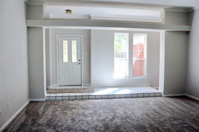 Entry way steps down into living area with wood burning fireplace. | Image 2