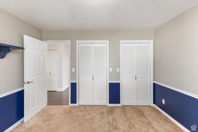 Unfurnished bedroom featuring baseboards, carpet flooring, two closets, and a textured ceiling | Image 15