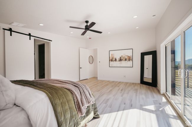 Bedroom featuring light wood-type flooring, access to exterior, a barn door, recessed lighting, and ceiling fan | Image 9