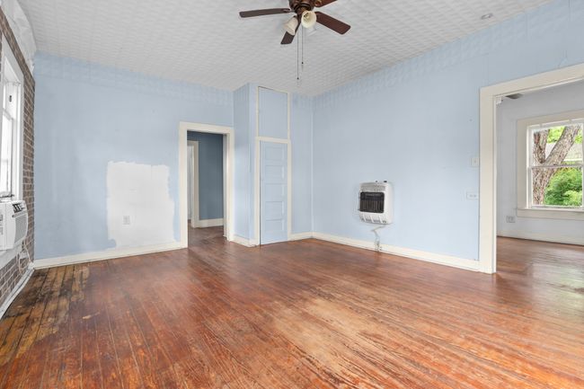 Unfurnished living room featuring heating unit, ceiling fan, wood-type flooring, and baseboards | Image 13