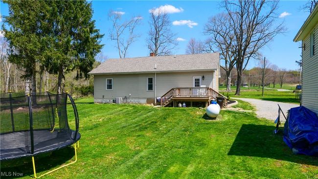 Back of property with a trampoline, a deck, a chimney, a lawn, and stairway | Image 32