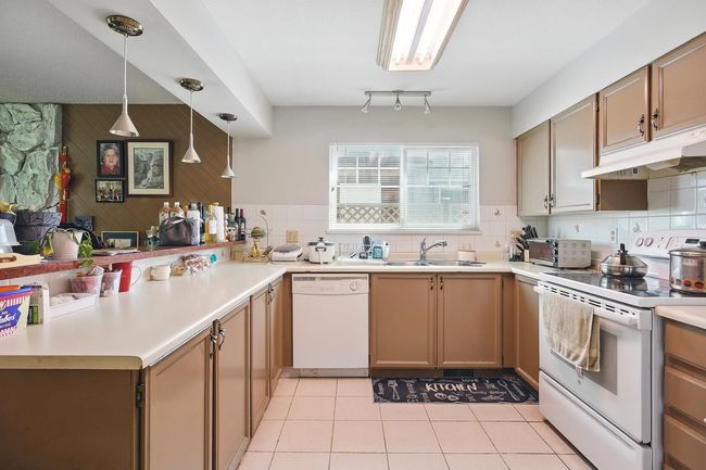 Kitchen featuring white appliances, a sink, under cabinet range hood, and light countertops | Image 4