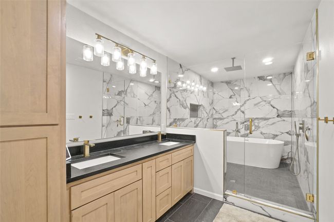 Bathroom featuring a marble finish shower, double vanity, a freestanding bath, and recessed lighting | Image 17