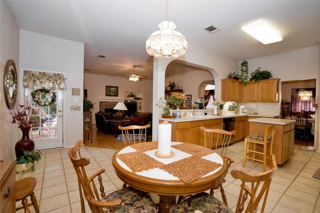 Dining space with light tile patterned floors, ceiling fan, a chandelier, and arched walkways | Image 14