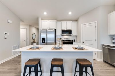 Stunning open concept kitchen with large center island and walk-in pantry for storage. Photo of Model Home. Options and colors may vary. | Image 1