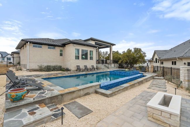 View of swimming pool featuring a fire pit, a patio area, a fenced backyard, and a pool with connected hot tub | Image 37