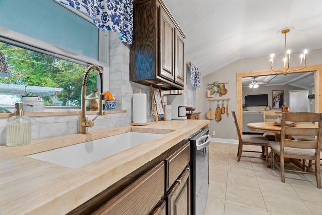 Kitchen with butcher block counters, vaulted ceiling, a ceiling fan, stainless steel dishwasher, and pendant lighting | Image 15