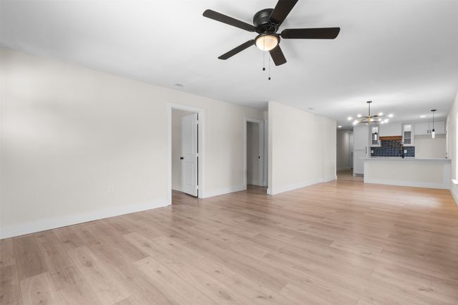 Unfurnished living room featuring a chandelier, light wood finished floors, and ceiling fan | Image 7