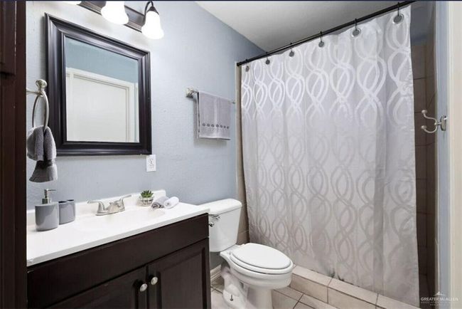 Bathroom with vanity, tile patterned flooring, and curtained shower | Image 8
