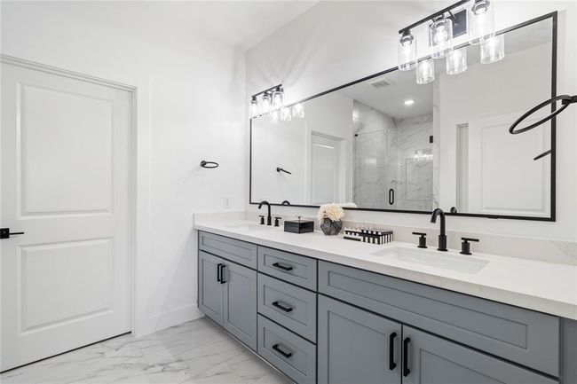 With soft gray cabinetry, quartz countertops, and chic black hardware, this bathroom combines sophistication with functionality. | Image 20