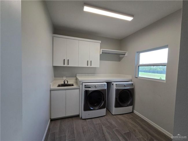 Laundry room with washer and dryer, cabinet space, baseboards, and wood finish floors | Image 8