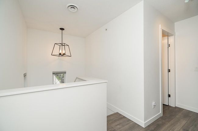 Hallway featuring baseboards, visible vents, wood finished floors, and an upstairs landing | Image 25
