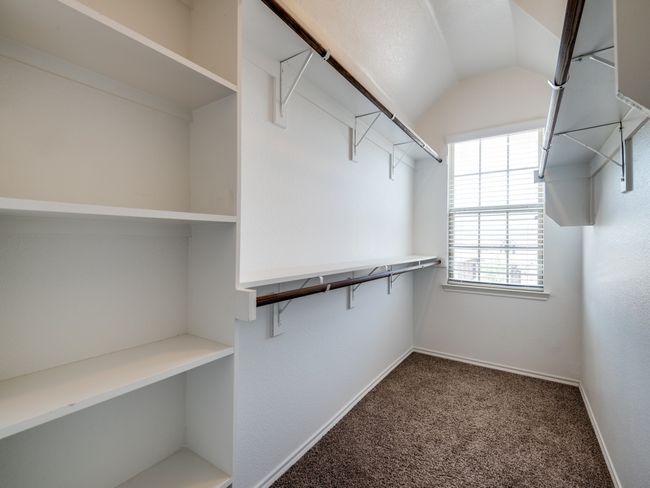 Large walk-in closet featuring vaulted ceiling and carpet flooring | Image 10