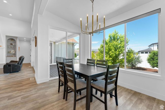 Dining area with light wood-type flooring, a chandelier, recessed lighting, and built in shelves | Image 10