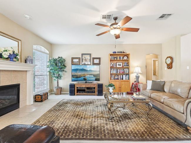 Living room with a ceiling fan, arched walkways, and a tile fireplace | Image 8