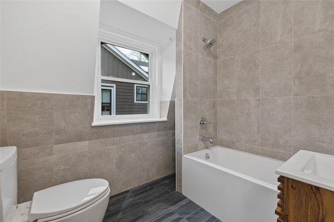 Full bath with toilet, vanity, shower / washtub combination, and tile walls | Image 18