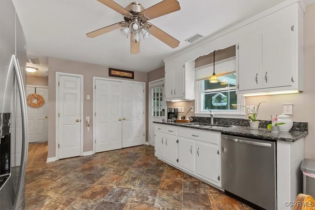Kitchen with stainless steel appliances, a sink, ceiling fan, dark stone finish flooring, and white cabinetry | Image 18