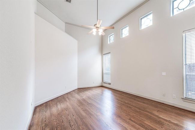 Primary bedroom on main level with 14' ceiling with fan and windows overlooking side yard. | Image 4