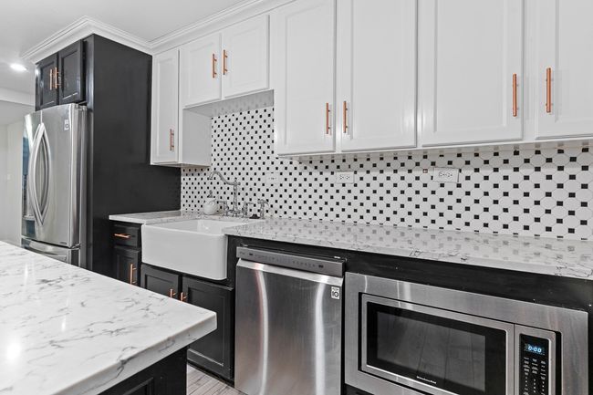 Kitchen with appliances with stainless steel finishes, backsplash, a sink, white cabinets, and light stone countertops | Image 20