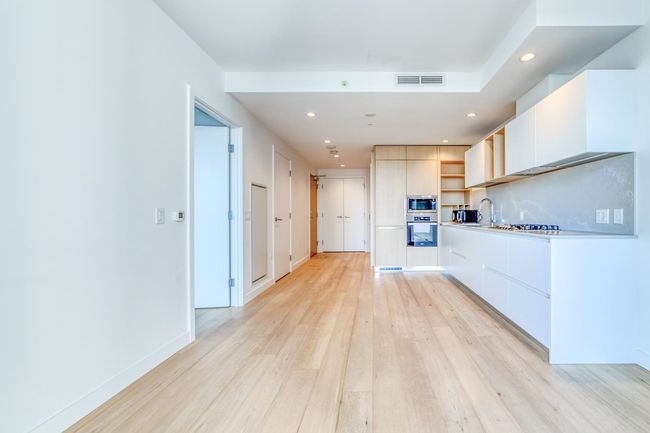 Kitchen featuring open shelves, stainless steel microwave, a sink, modern cabinets, and light wood-type flooring | Image 6