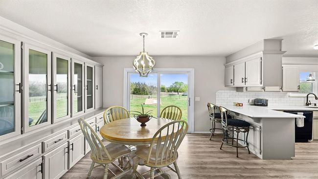 Dining area with a notable chandelier, light wood finished floors, and visible vents | Image 33
