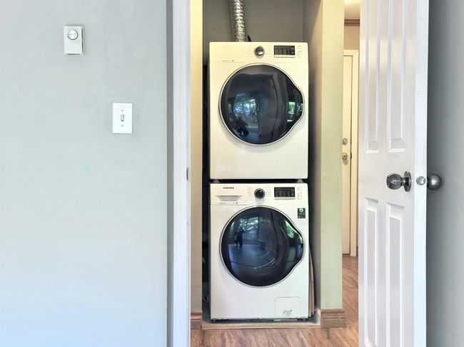 Clothes washing area with estacked washer and dryer and wood finished floors | Image 13