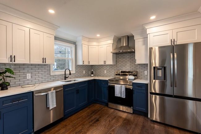 Kitchen featuring stainless steel appliances, blue cabinetry, a sink, and wall chimney range hood | Image 7