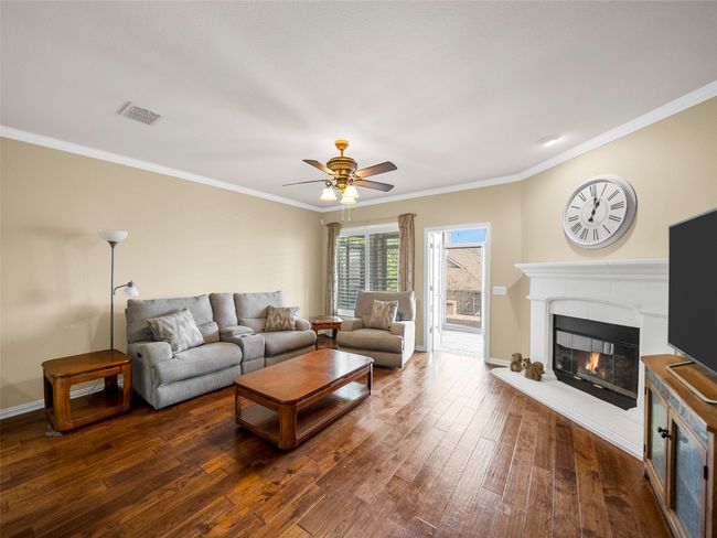 Living room featuring ornamental molding, hardwood / wood-style floors, and a glass covered fireplace | Image 13