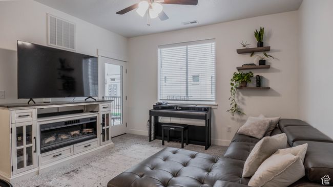 Carpeted living room featuring visible vents, a ceiling fan, and baseboards | Image 4