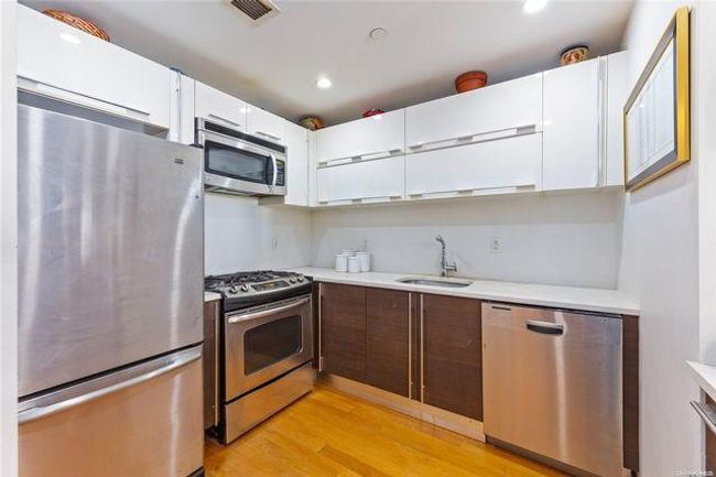 Kitchen featuring sink, stainless steel appliances, white cabinets, and light wood-type flooring | Image 7