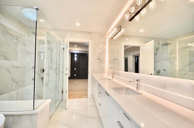 Bathroom featuring a marble finish shower, marble tiled flooring, double vanity, and recessed lighting | Image 29