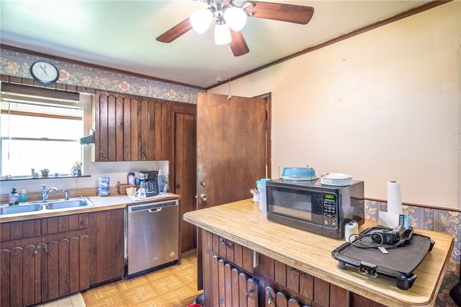 Kitchen featuring dishwasher, black microwave, light countertops, and ceiling fan | Image 28