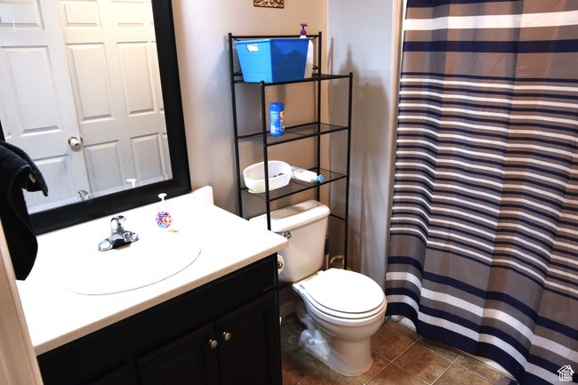Full bath with tile patterned flooring, a shower with shower curtain, toilet, and vanity | Image 10