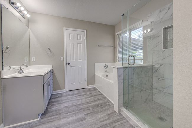 Bathroom featuring vanity, a garden tub, a marble finish shower, wood finished floors, and a textured wall | Image 15