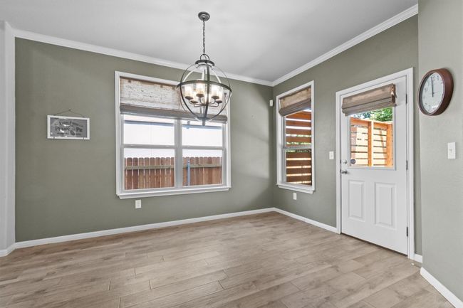Unfurnished dining area featuring a chandelier, crown molding, wood finished floors, and baseboards | Image 17