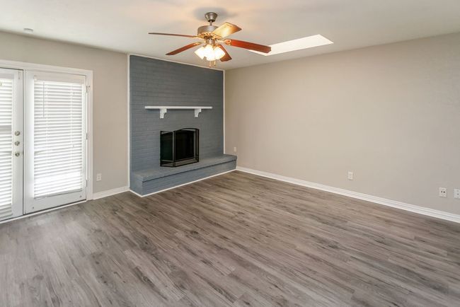 Kitchen featuring stainless steel appliances, under cabinet range hood, white cabinets, light wood finished floors, and washer / dryer | Image 5