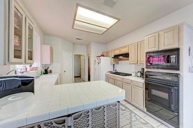 Kitchen featuring black appliances, tile counters, and tasteful backsplash | Image 19