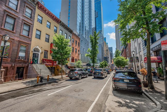 View of asphalt road with sidewalks, stairway, a city view, curbs, and street lights | Image 25
