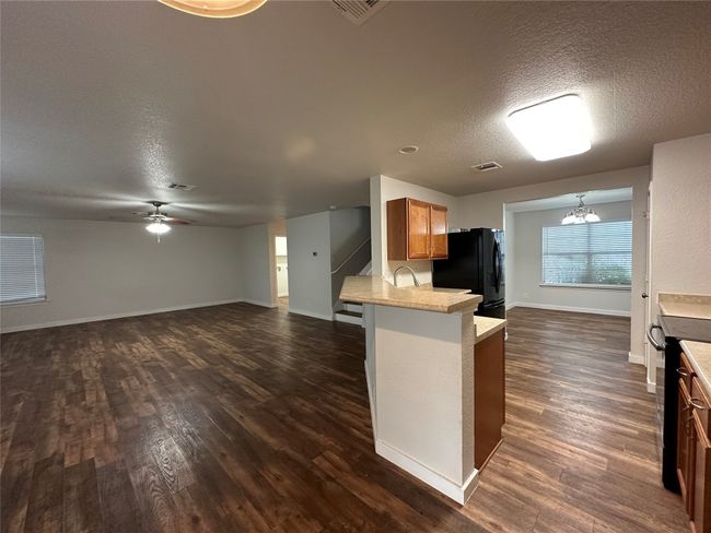 Kitchen with a textured ceiling, dark wood-style flooring, a chandelier, a ceiling fan, and light countertops | Image 17