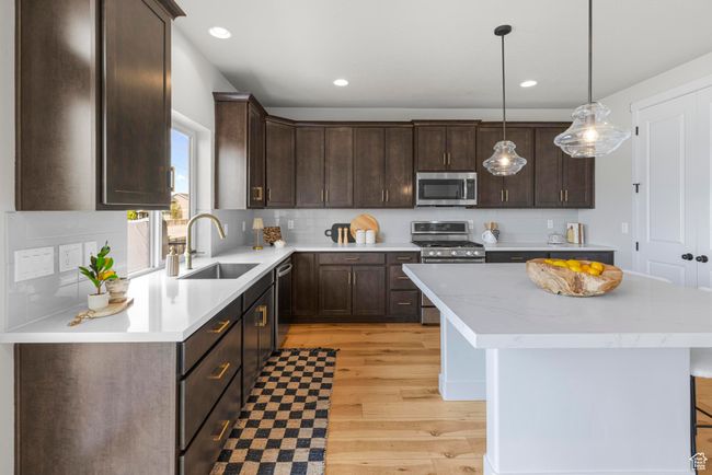 Kitchen featuring a center island, stainless steel appliances, dark brown cabinets, and a sink | Image 13