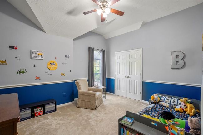 This charming upstairs bedroom features a vaulted ceiling with unique architectural details, adding character and depth to the space. The elegant chair railing complements the design, while double doors open to a spacious closet, offering plenty of storage. | Image 29