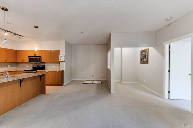 Kitchen with a kitchen breakfast bar, brown cabinets, light carpet, and light stone countertops | Image 7