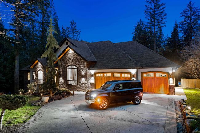 French country home with stone siding, concrete driveway, an attached garage, and a shingled roof | Image 4
