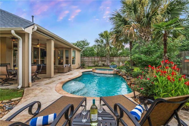 View of swimming pool with a fenced backyard, a patio area, ceiling fan, and a pool with connected hot tub | Image 9