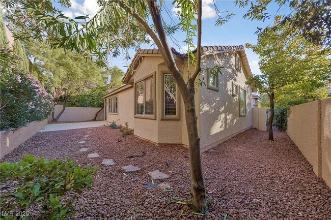 View of property exterior featuring stucco siding, a fenced backyard, a patio area, and a tile roof | Image 11