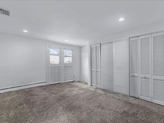 Unfurnished bedroom with carpet, multiple closets, recessed lighting, and a baseboard radiator | Image 24
