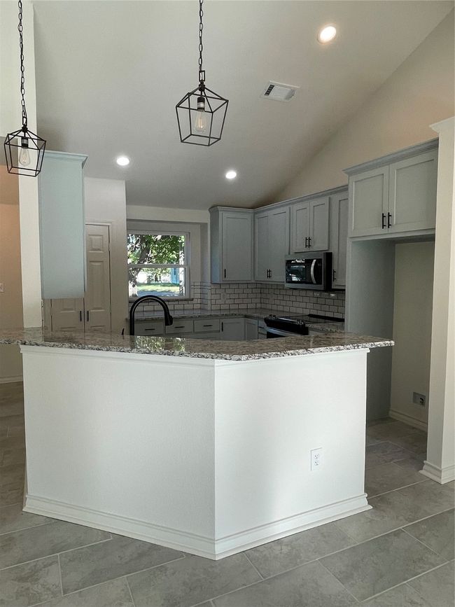 Kitchen featuring decorative light fixtures, light stone countertops and decorative backsplash | Image 19