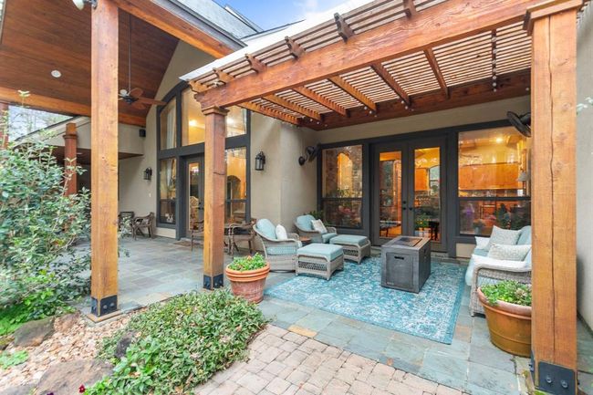 The outdoor living space extends the square footage of this estate further and provides the perfect place to enjoy the serenity of nature. The back porch boasts a soaring 22' vaulted, tongue and groove ceiling and the cedar pergola features wall-mounted oscillating fans to provide respite from the Texas heat. The slate tile floor, with its natural patina, enhances the peaceful, natural surroundings. | Image 35