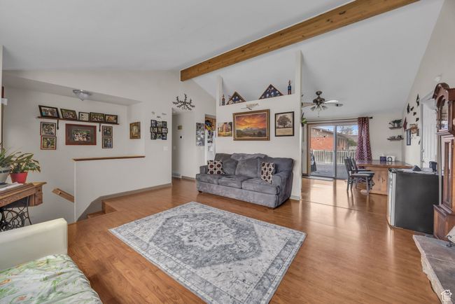 Living area with lofted ceiling with beams, ceiling fan, and wood finished floors | Image 7